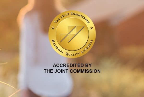 The Joint Commission Gold Seal award badge with a woman out of focus in the background.
