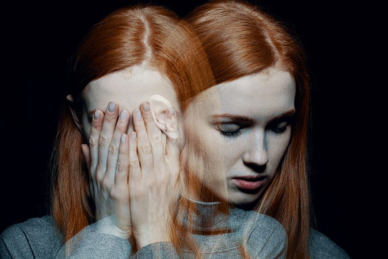 Superimposed images of the same red haired woman, one with her gazing downward and the other with her hands covering her face.