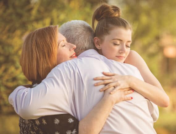Father hugging his wife and daughter.
