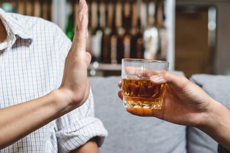 A man who knows how to stop drinking holds up his hand to decline a drink being offered to him.