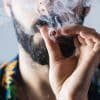 Man with a beard smoking weed in a joint.