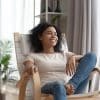 Woman taking time for self-care, relaxing in comfortable chair smiling and looking out the window.