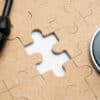 A stethoscope sitting atop a puzzle with a missing piece.